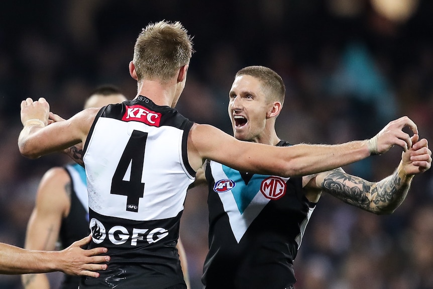 Two AFL teammates embrace after a goal