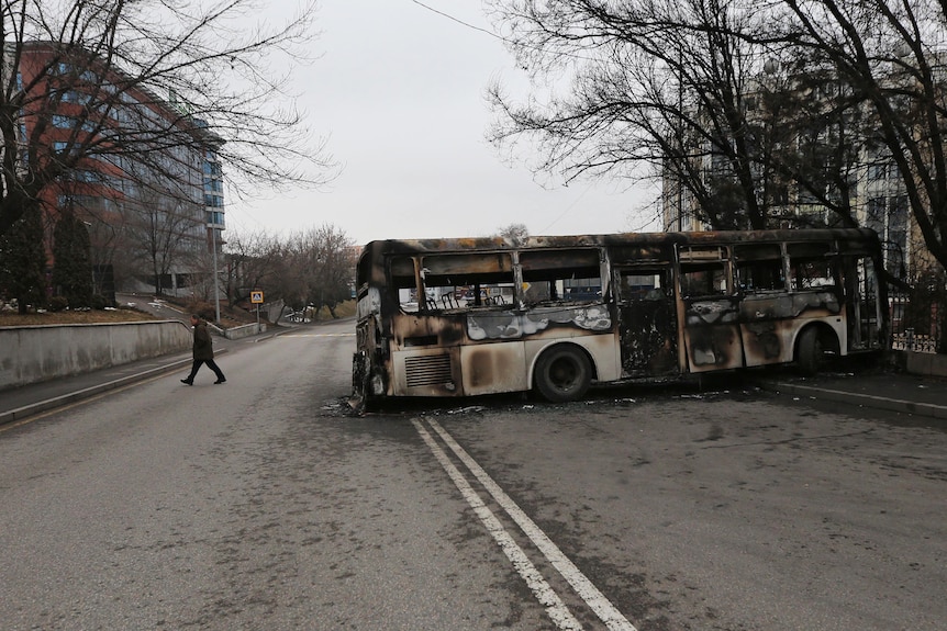 A man walks past a burnt out bus. It was set on fire during the protests in Almaty, Kazakhstan, January 9, 2022.
