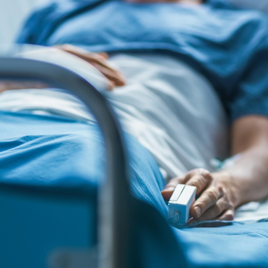 A patient in a hospital bed with a pulse monitor connected to their finger