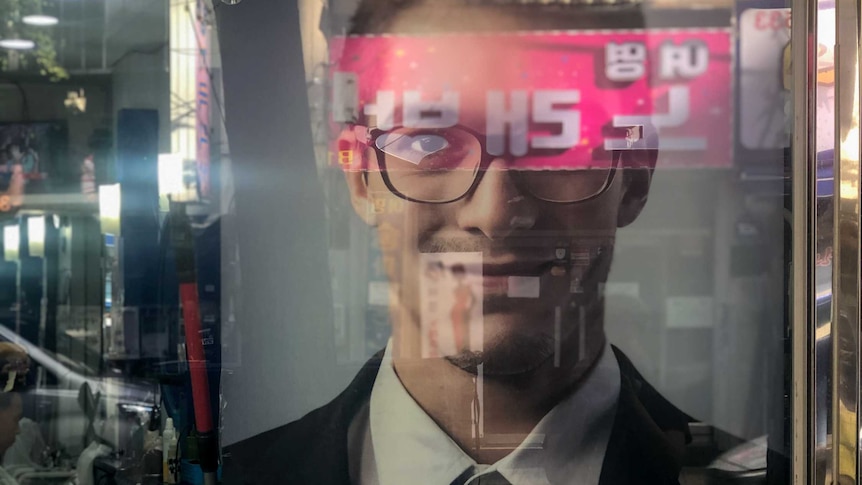 A picture of a smiling man and sign that reads 'Men's beauty shop' in a shop window.