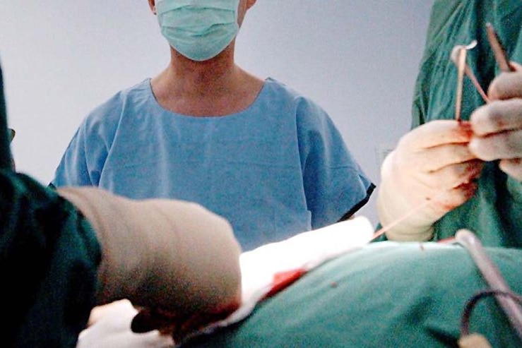 A close-up of gowned surgeons in an operating theatre.