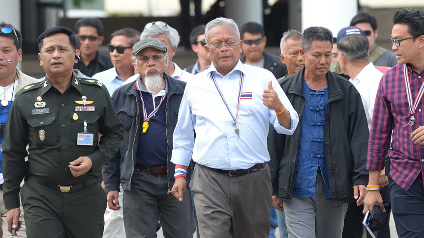 Thai protest leader Suthep Thaugsuban (C) walks with his staff prior to meeting with Thai military chiefs at the Thai Armed Forces headquarters in Bangkok on December 14, 2013.