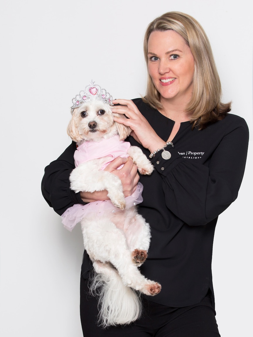 Kym Ryan smiles for a photo while holding her tutu-wearing dog, Missy.
