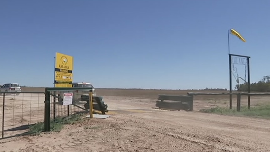 Queensland Police vehicles enter the large cotton farm