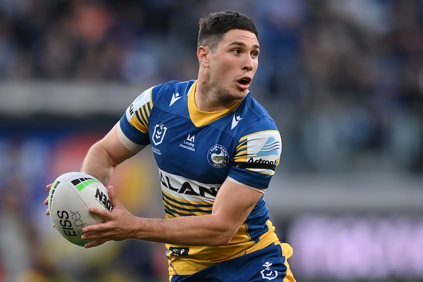 A Parramatta Eels NRL player holds the ball in two hands as he prepares to pass.
