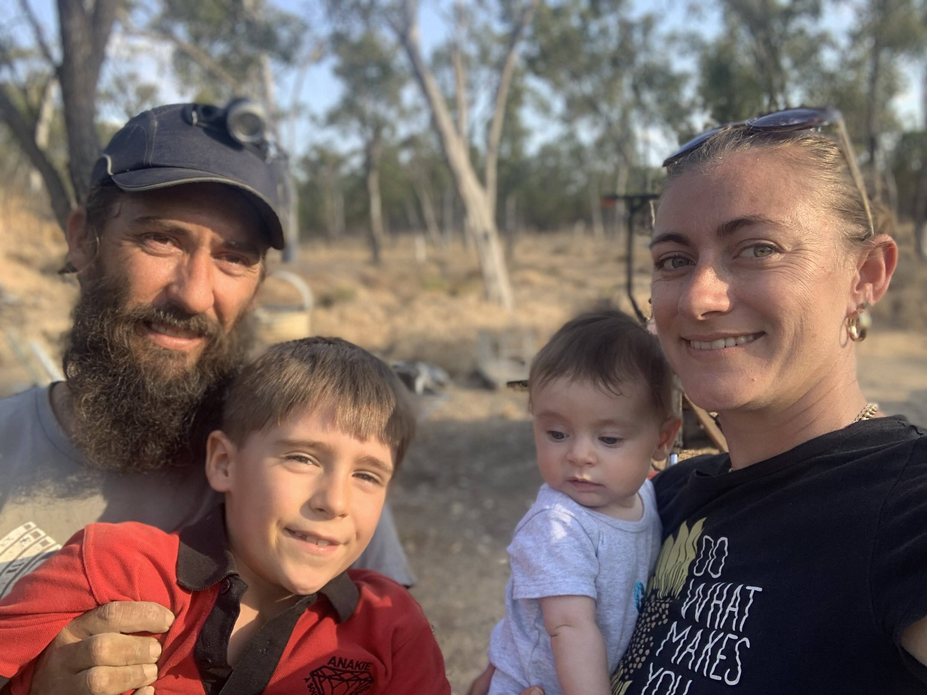 a man and woman smile with their two children, a young boy and a baby girl