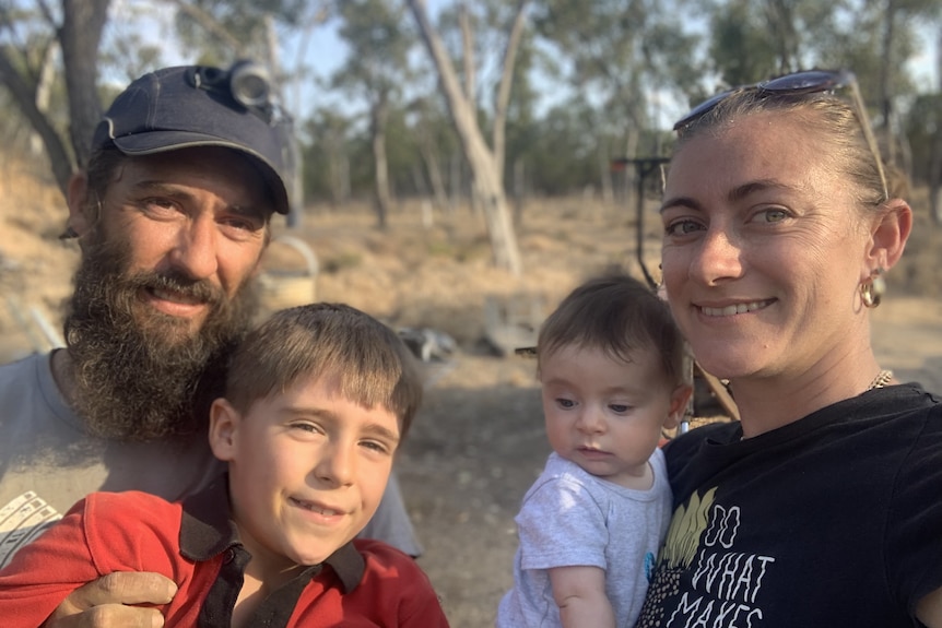 a man and woman smile with their two children, a young boy and a baby girl