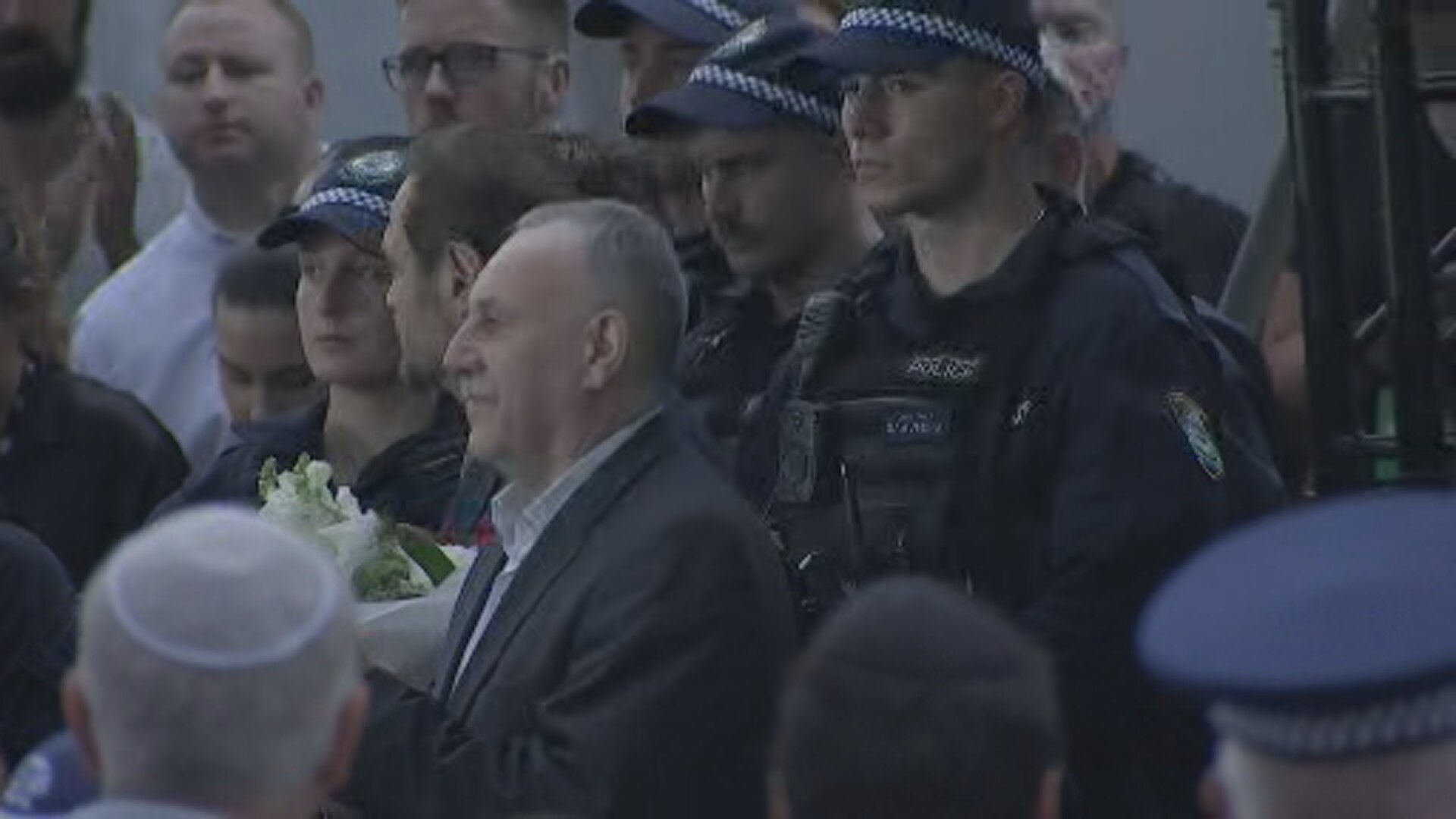 man stands surrounded by people including police