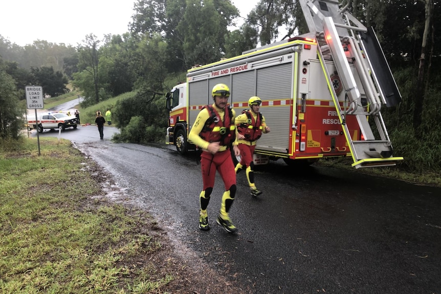 Swift water rescue teams run up flooded path.