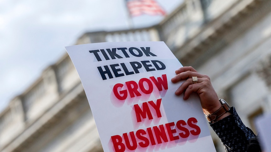 A sign held up in front of congress says TikTok helped grow my business 