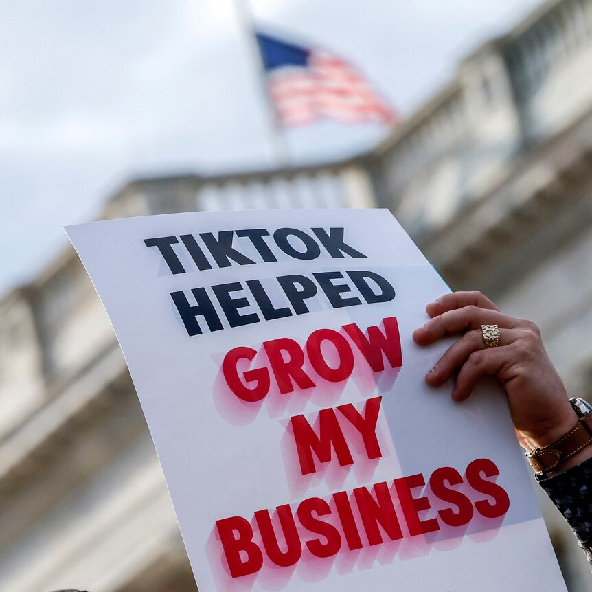 A sign held up in front of congress says TikTok helped grow my business 