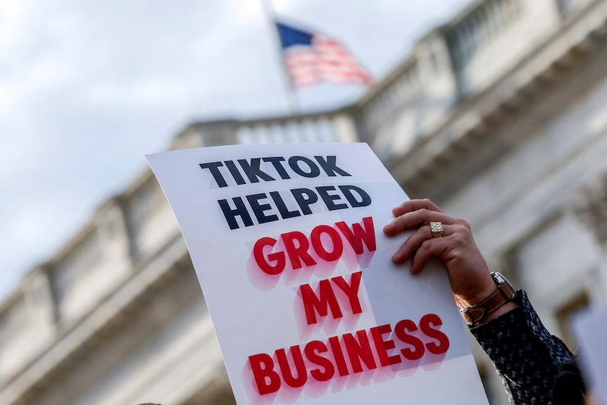 A sign held up in front of congress says TikTok helped grow my business 