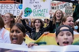 A group of students protest with signs. In centre one holds a sign saying "We'll die of climate change". 