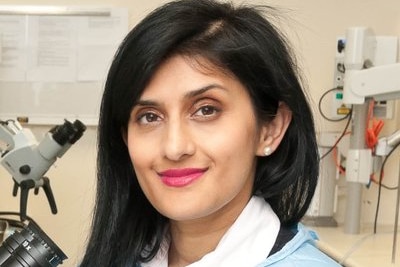 Dr Payal Mukherjee wears scrubs and poses with medical equipment.