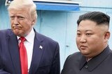 Donald Trump looks to the left and purses his lips as he clutches Kim Jong-un's hand.