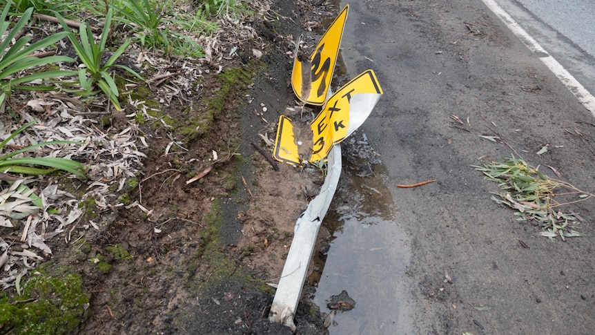 A road sign runover and left in mud.