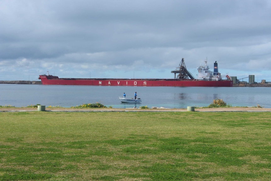 Men fish near a ship at Esperance Port