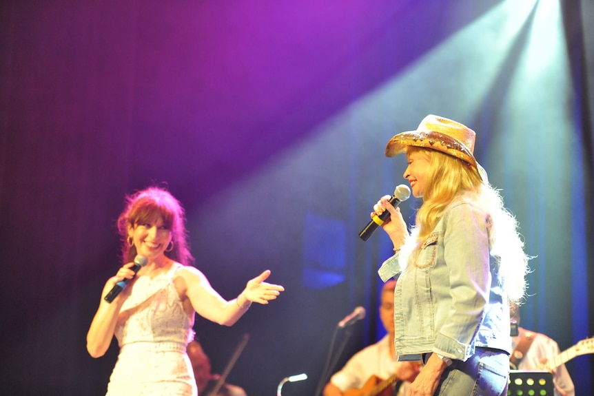 two women on stage holding microphones 