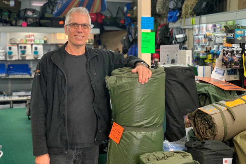 A man leans on a camp mattress inside a camping shop