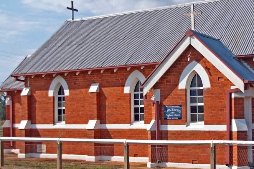 Red brick building with white facades, tin roof and crosses