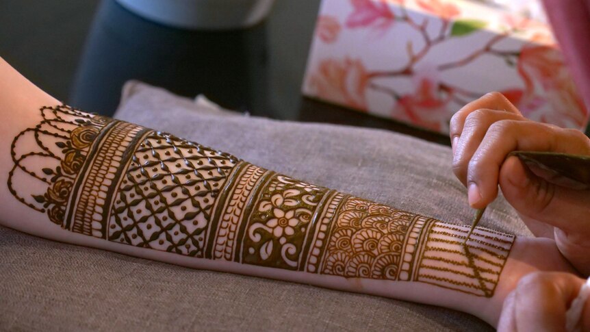 A forearm covered in an intricate henna design