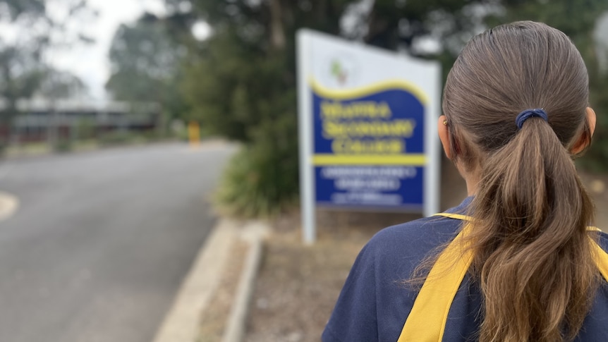 Back of the head of a girl standing in front of blurred Maffra Secondary College sign
