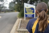 Back of the head of a girl standing in front of blurred Maffra Secondary College sign
