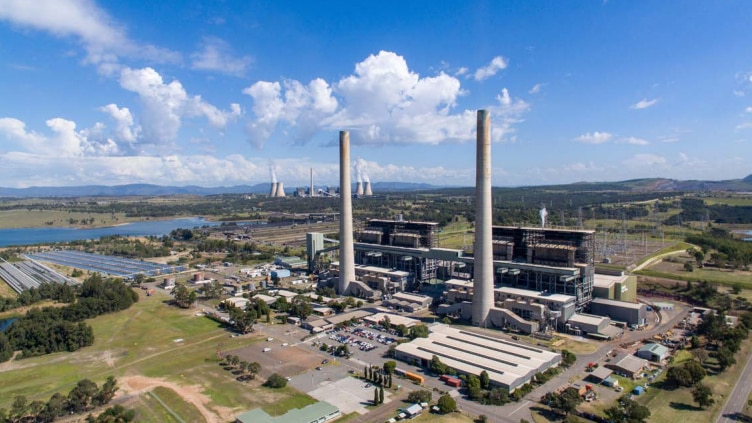 Two turbines stand tall at the Liddell power station on a clear day with blue skies.