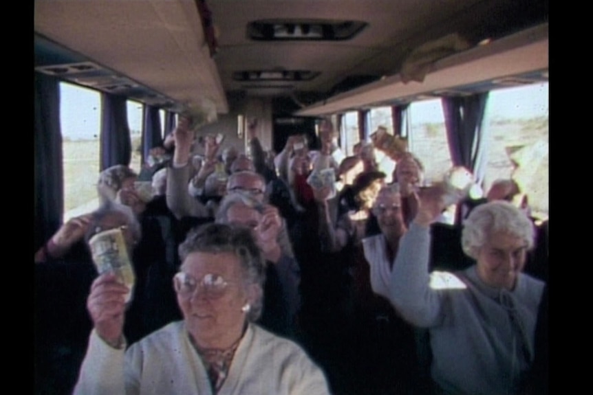 A bus full of older people wave money in the air.