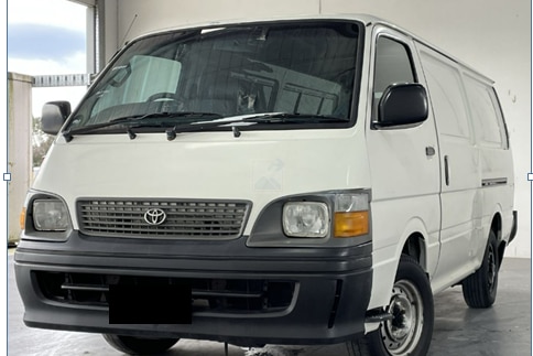 A white, older model Toyota HiAce van.