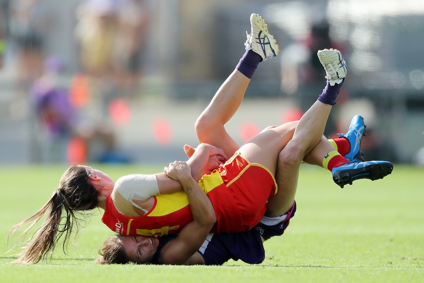 Claudi Whitfort (top) is tackled by Kiara Bowers who lies on the turf