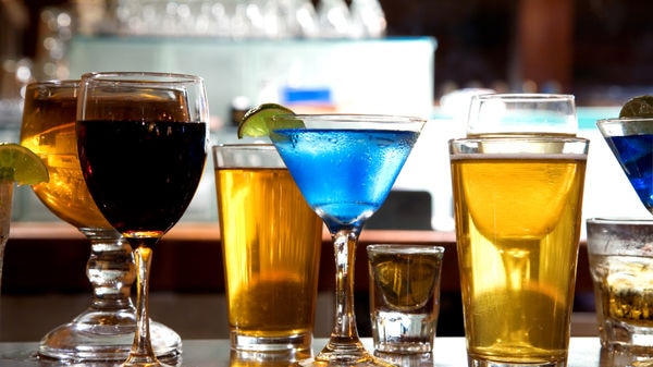 Various alcoholic drinks lined up on a bar.