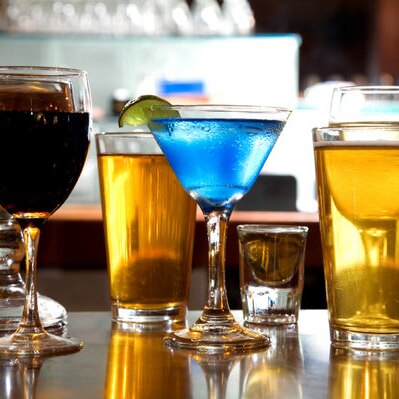 Various alcoholic drinks lined up on a bar.