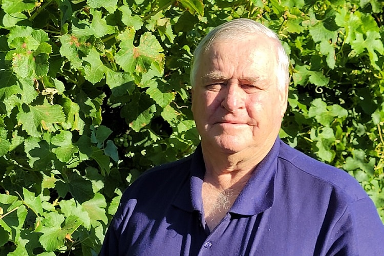 Mr Brombal standing in front of some vines