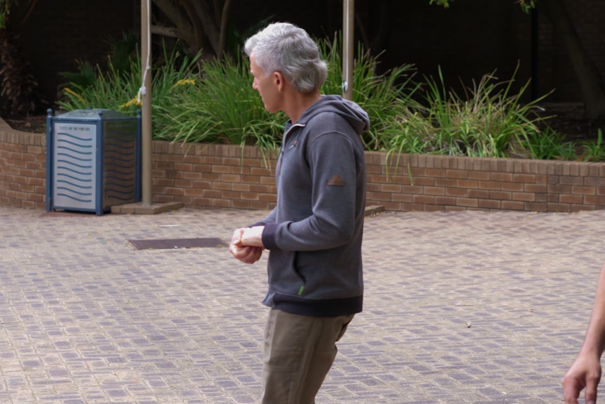 A man walks on a brick pavement.