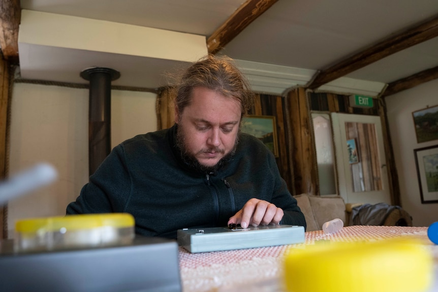 A man looks down at a box with a bumblebee on it