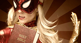 A woman wearing a superhero outfit holds a Holy Bible