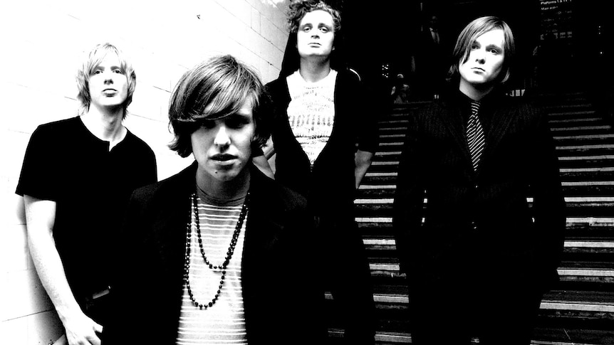 Black and white photo of band British India standing on the steps of a train station
