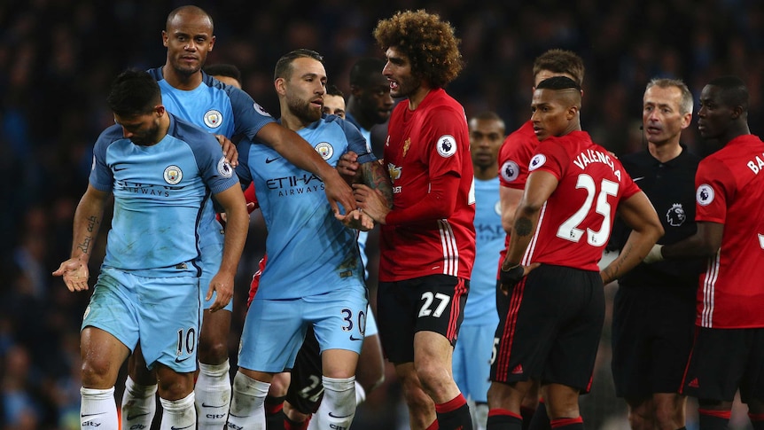Marouane Fellaini tries to get at Sergio Aguero after getting a red card for a headbutt