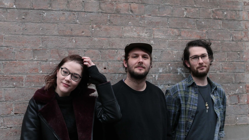 The three designers, all in their early to mid-twenties, standing against a brick wall in a Melbourne alleyway.