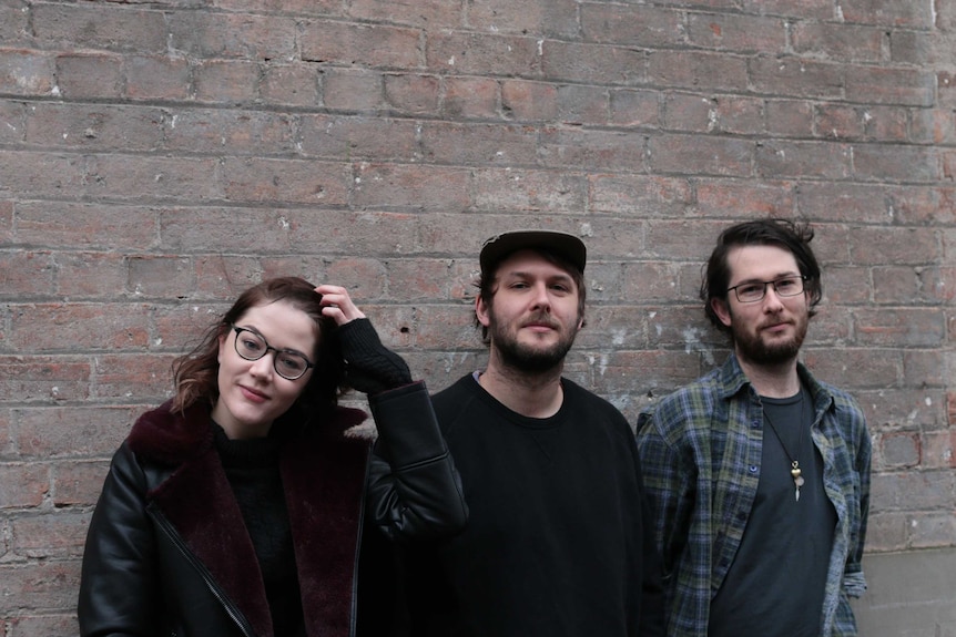 The three designers, all in their early to mid-twenties, standing against a brick wall in a Melbourne alleyway.