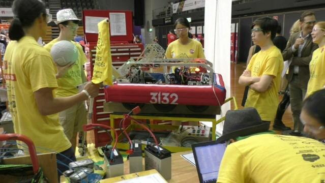 Team of young people stand around robotic vehicle
