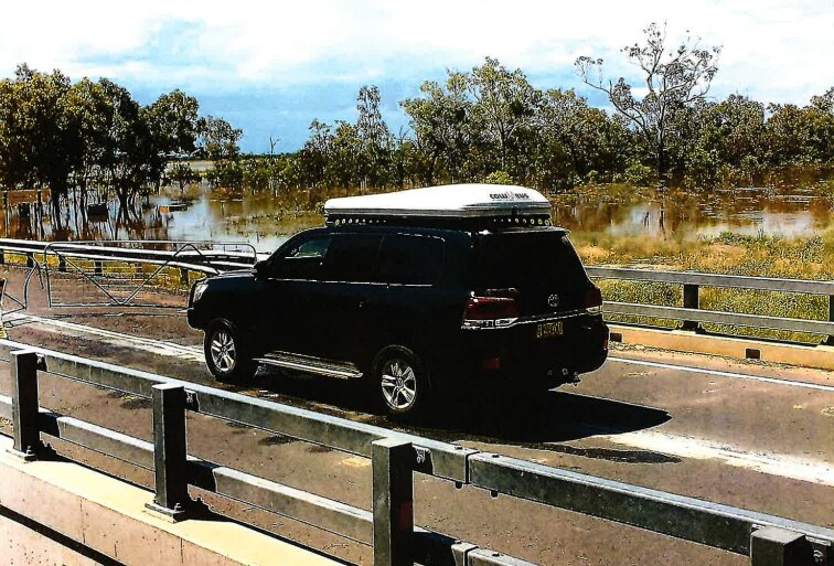 An image from a security camera of a black landcruiser driving towards a closed gate cutting access to a roadway