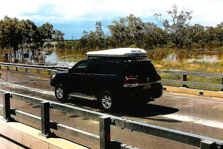 An image from a security camera of a black landcruiser driving towards a closed gate cutting access to a roadway