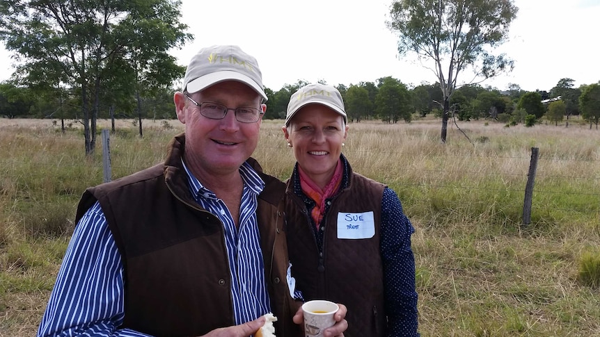 Jeff and Sue Trott stand side by side in front of a paddock