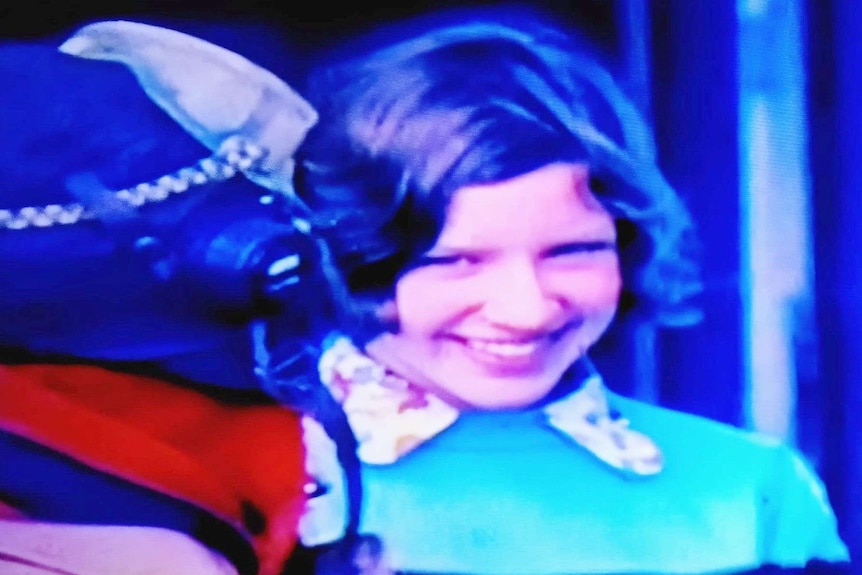 Film still of a young woman with bobbed hair smiling at a woman wearing a flying helmet