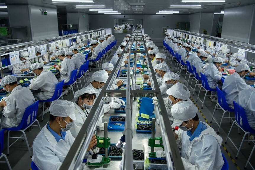 Workers make pods for e-cigarettes on a production line