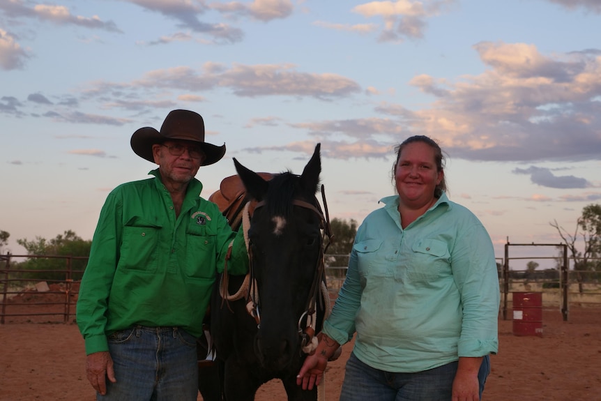 Man and woman standing next to a horse. 