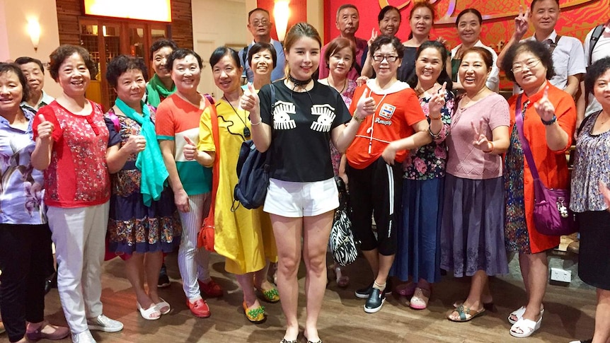 Chinese tourist Gina Li (centre) stands with a group of fellow tourist at a restaurant in Cairns in far north Queensland.