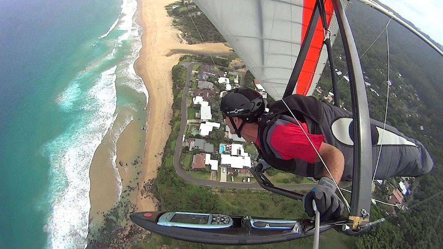 Illawarra hang glider pilot Tony Armstrong flies his glider in the air over Stanwell Park, the view is looking down.